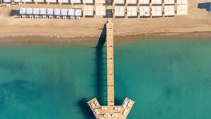 An aerial view of a pier with a boat dock, surrounded by a beach with rows of sun loungers. - Royal Wings Hotel - All Inclusive (Antalya)
