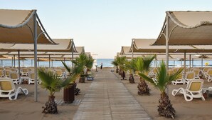 A beachside walkway leading to beach umbrellas and lounge chairs. - Royal Dragon Hotel – All Inclusive (Manavgat)