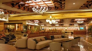 A spacious lobby with a central seating area, a reception desk, and a staircase leading to other floors. - Royal Dragon Hotel – All Inclusive (Manavgat)