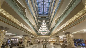 A spacious lobby with a high ceiling, a central chandelier, and patterned floor tiles. - Royal Alhambra Palace – All Inclusive (Manavgat)