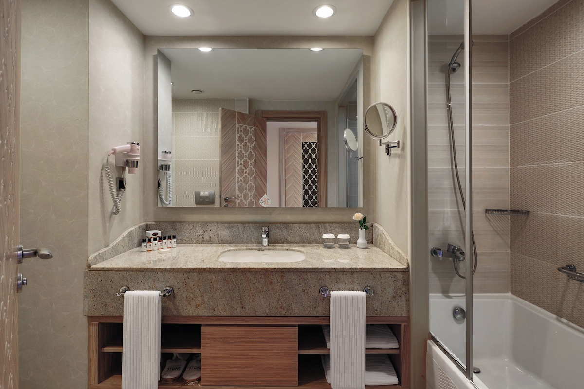 A modern bathroom with two sinks, a large mirror, a hairdryer, and a shower area.