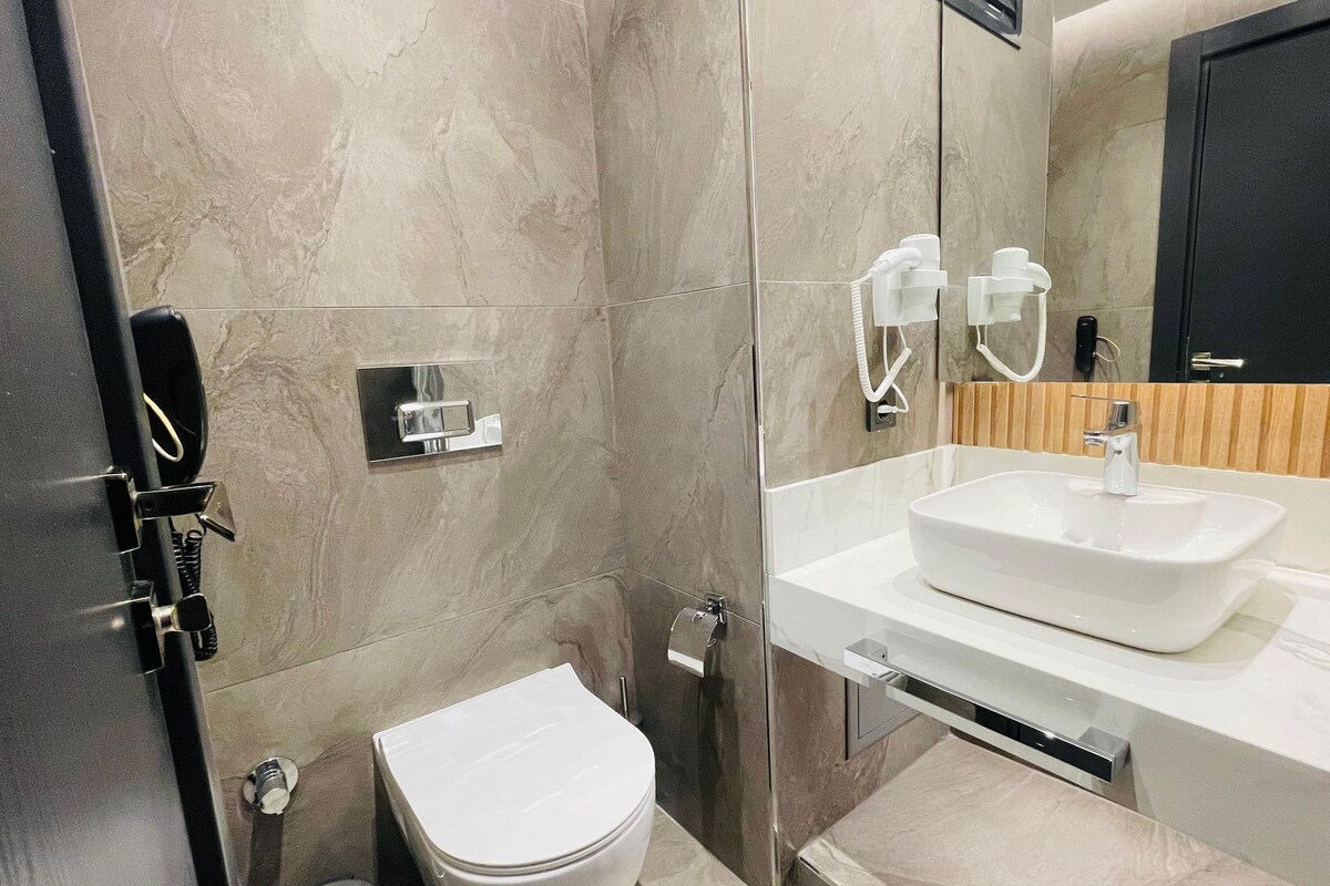 Une salle de bain moderne avec un lavabo blanc, des toilettes et un espace douche.