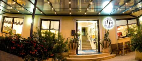 Un hotel con varios balcones, acceso de vidrio y un área exterior bien iluminada.