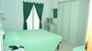 A bedroom with a bed, a desk with a computer, a wardrobe, and a window with curtains. - Philadelphia (Cattolica)