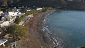 Un pueblo costero con una playa, edificios y una colina al fondo.