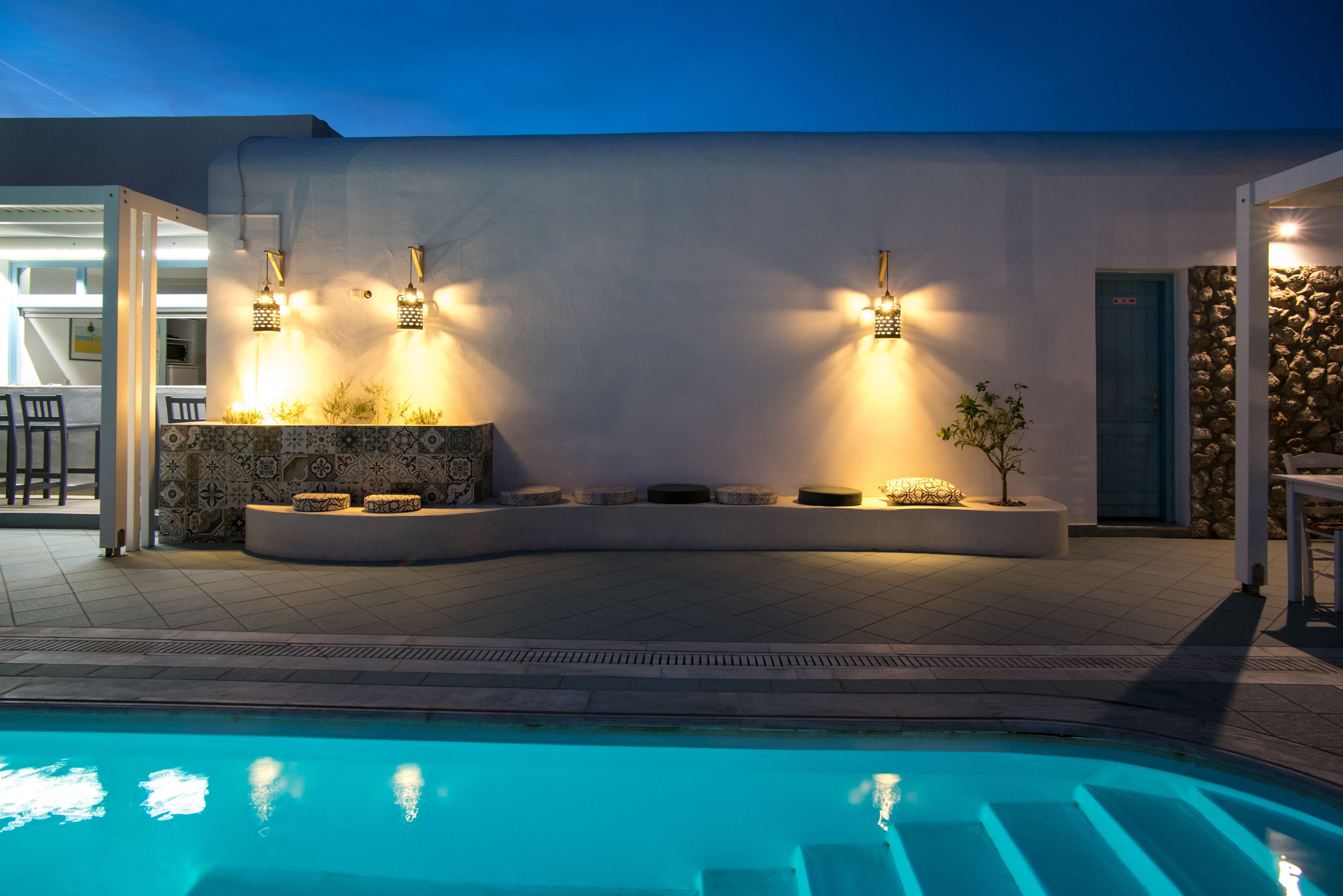 A poolside area with a modern design, including a pool, seating areas, and wall-mounted lighting.