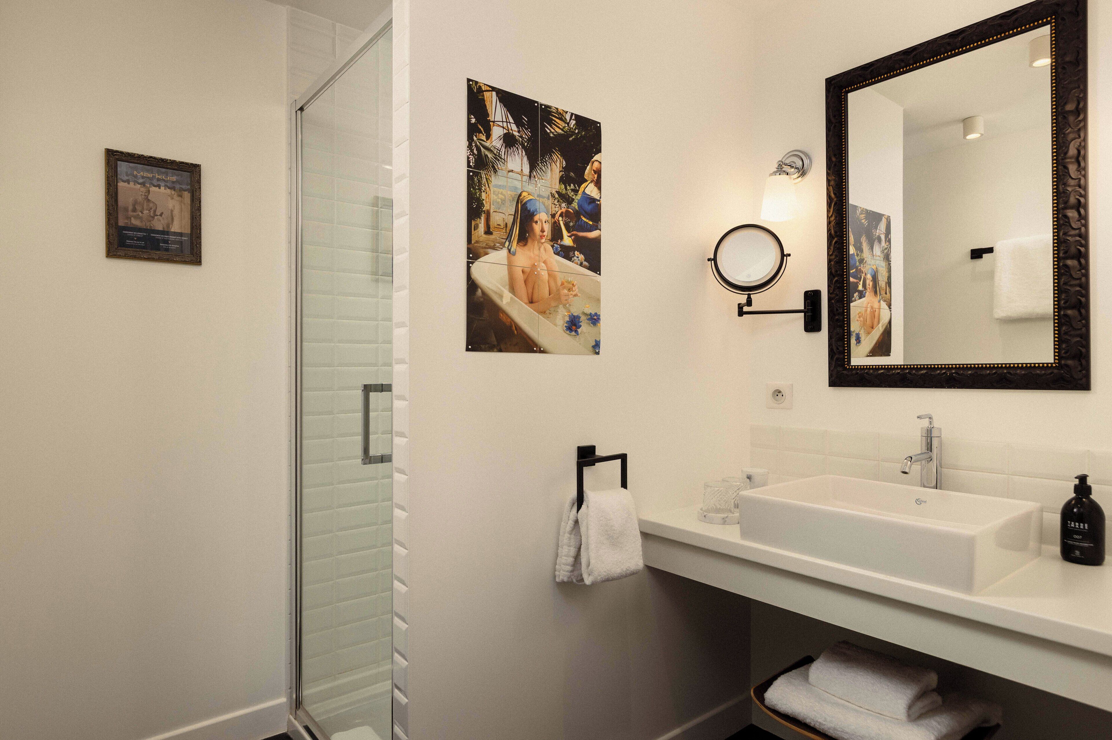 Un baño con un lavamanos blanco, un espejo grande y un cuadro en la pared.