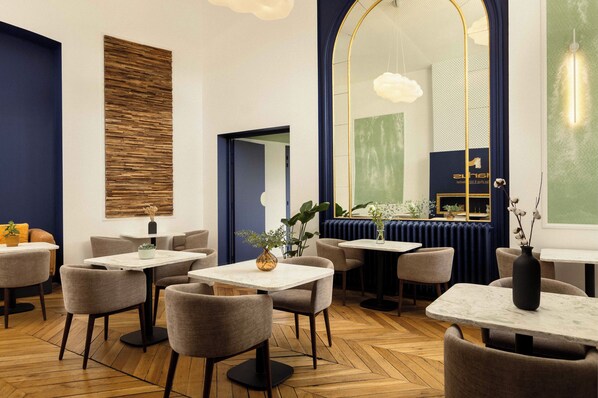 A modern restaurant with wooden flooring, round tables, and grey chairs. - Markus (Angers)