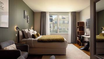 A modern bedroom with a bed, a desk, and a chair. There are curtains on the window, and a mirror is on the wall.