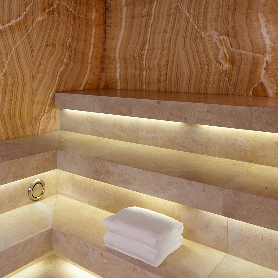 A bathroom with marble walls and a built-in bench.