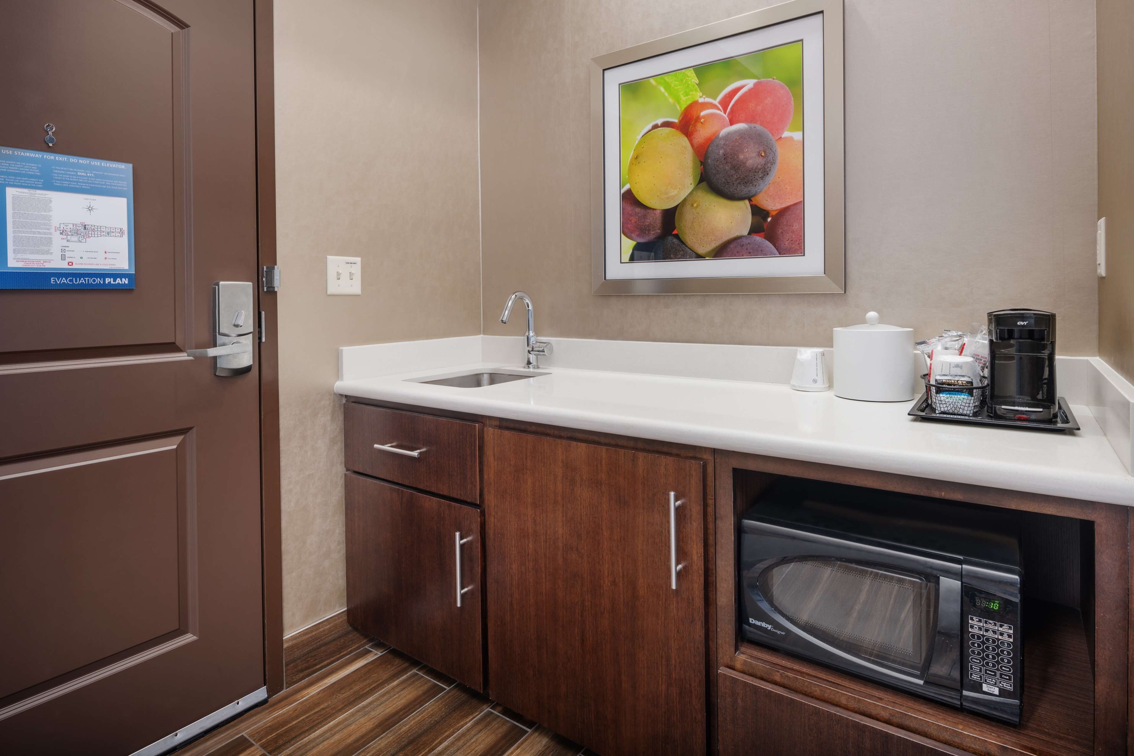 Una cocina de hotel con un lavamanos, microondas y cafetera.