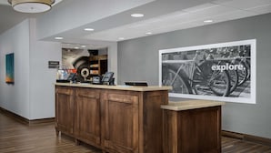A reception desk with a wooden finish, a digital kiosk, and a large framed photo of bicycles on the wall.