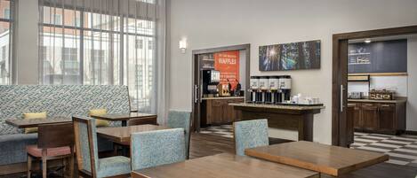 A hotel lobby with seating areas, a coffee station, and a waffle station.