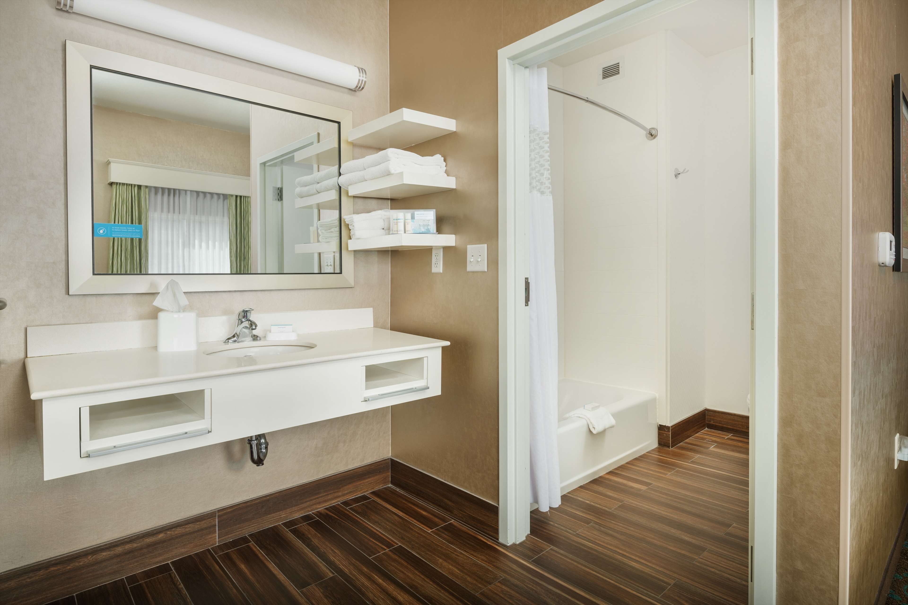 Une salle de bain moderne avec un grand miroir, un meuble-lavabo blanc et une douche à l’italienne.