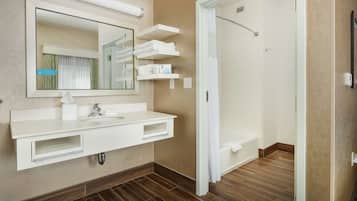 Une salle de bain moderne avec un grand miroir, un meuble-lavabo blanc et une douche à l’italienne.