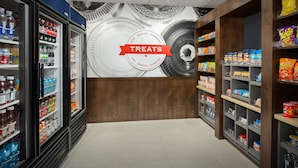 A grocery store interior with refrigerated sections on the left and shelves stocked with snacks and sundries on the right.