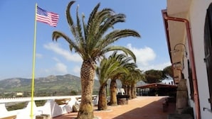 Terraço com palmeiras, uma bandeira americana e vista para montanhas.