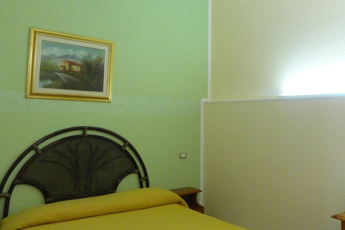 A room with a bed, a painting on the wall, and a ceiling with a white trim.