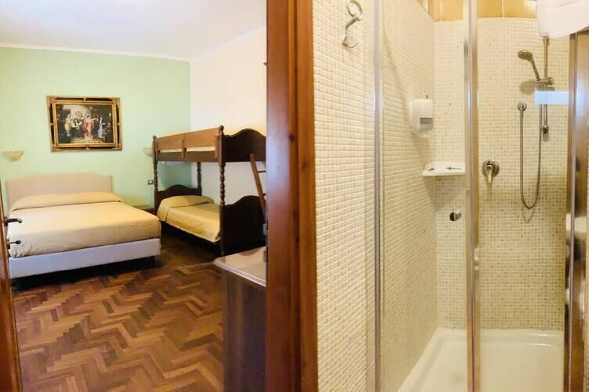 A room with bunk beds, a shower, and a toilet.
