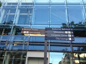 A directional sign with arrows pointing to various landmarks such as the Musical Theater, Badischer Bahnhof, Messeplatz, Congress Center, and City Lounge.
