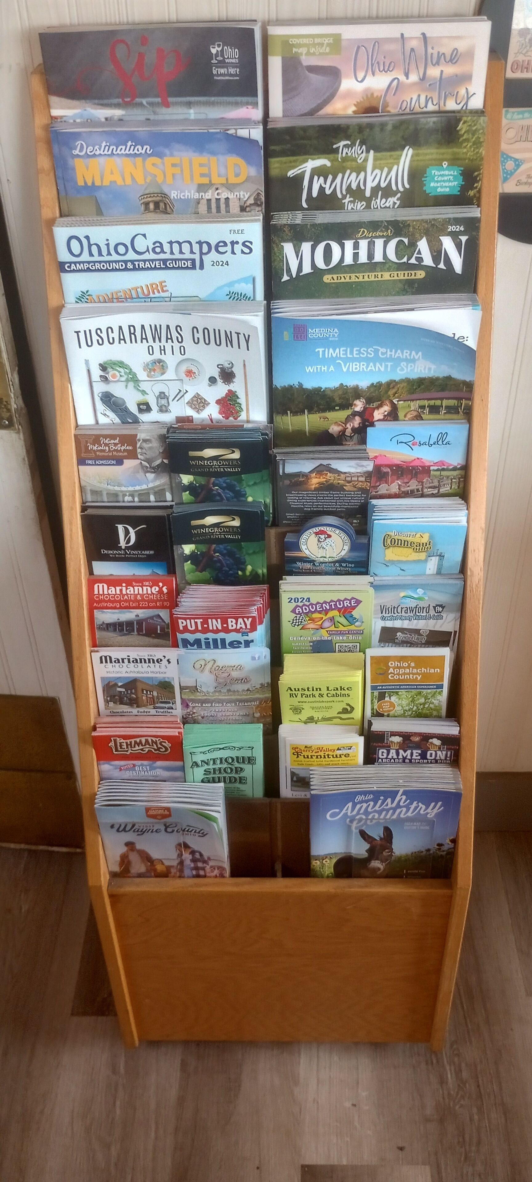 A display stand with various travel guides and maps for Ohio, including destinations like Mansfield, Tuscarawas County, and the Timeless Charm of Medina County.