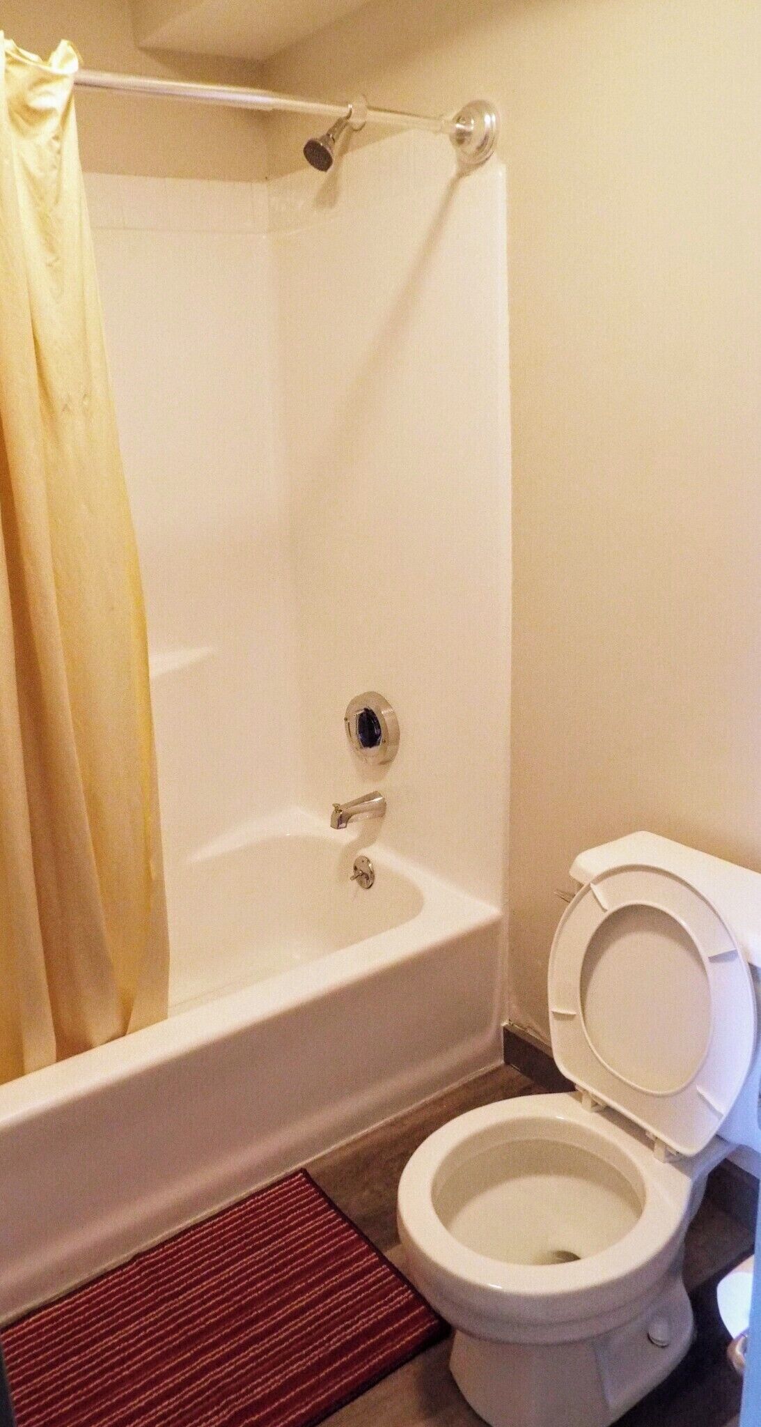 A bathroom with a bathtub, toilet, and shower curtain.