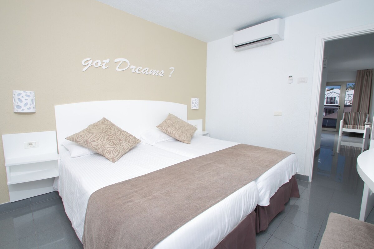 Un dormitorio moderno con cama, mesita de noche y aire acondicionado instalado en la pared.