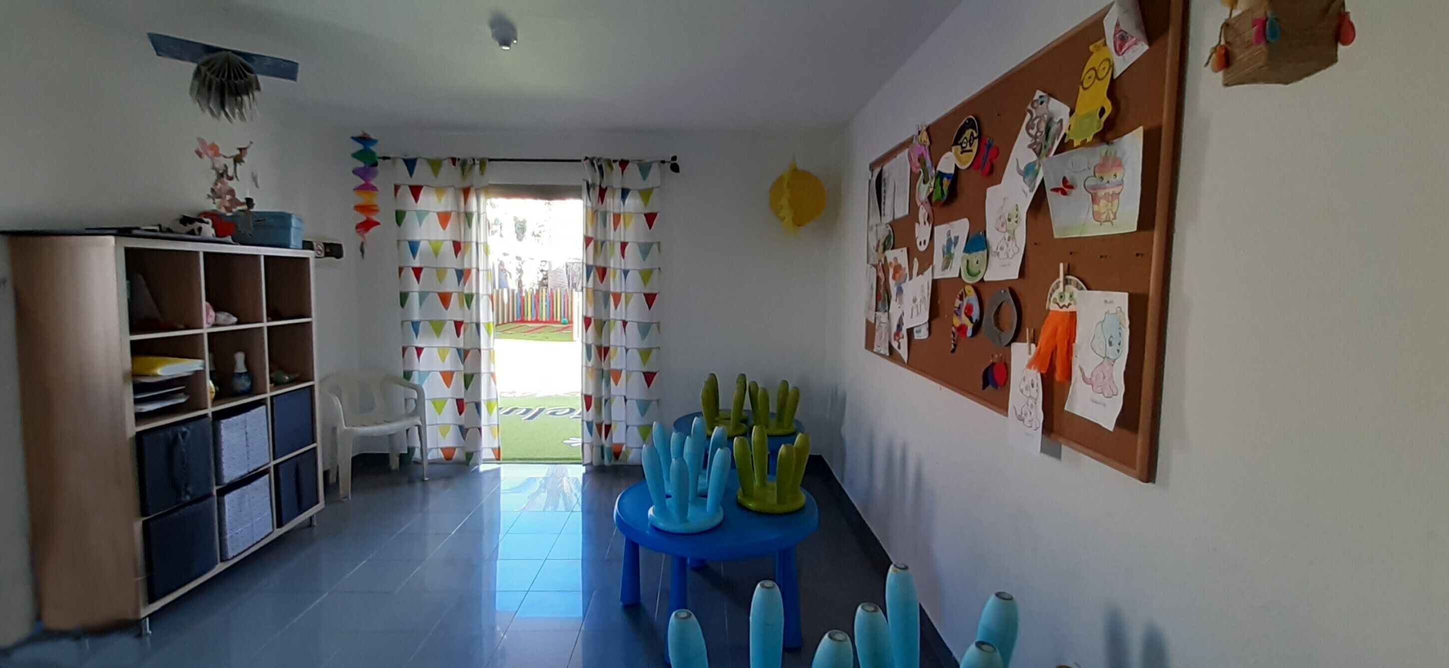 Un aula con un tablón de anuncios, una mesa azul y una pizarra.
