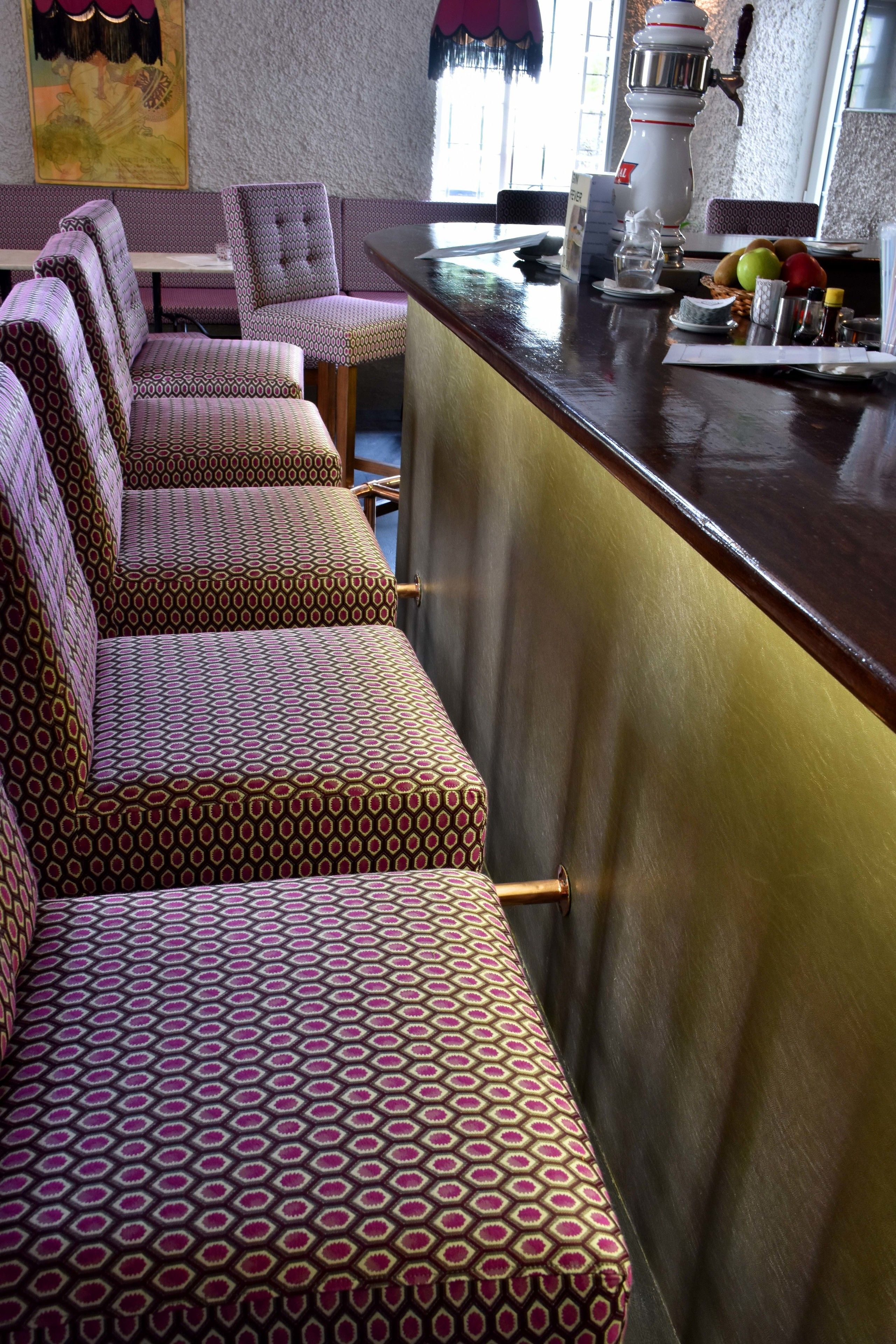 Zona de bar con asientos estampados y mostrador con varios artículos.