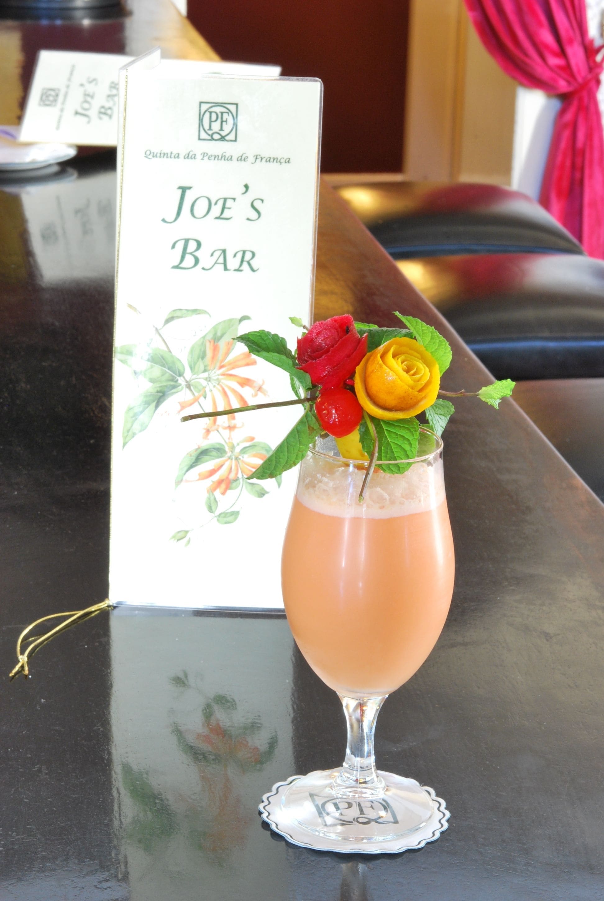 A bar setting with a menu board labeled "Joe's Bar" and a cocktail with a rose garnish.
