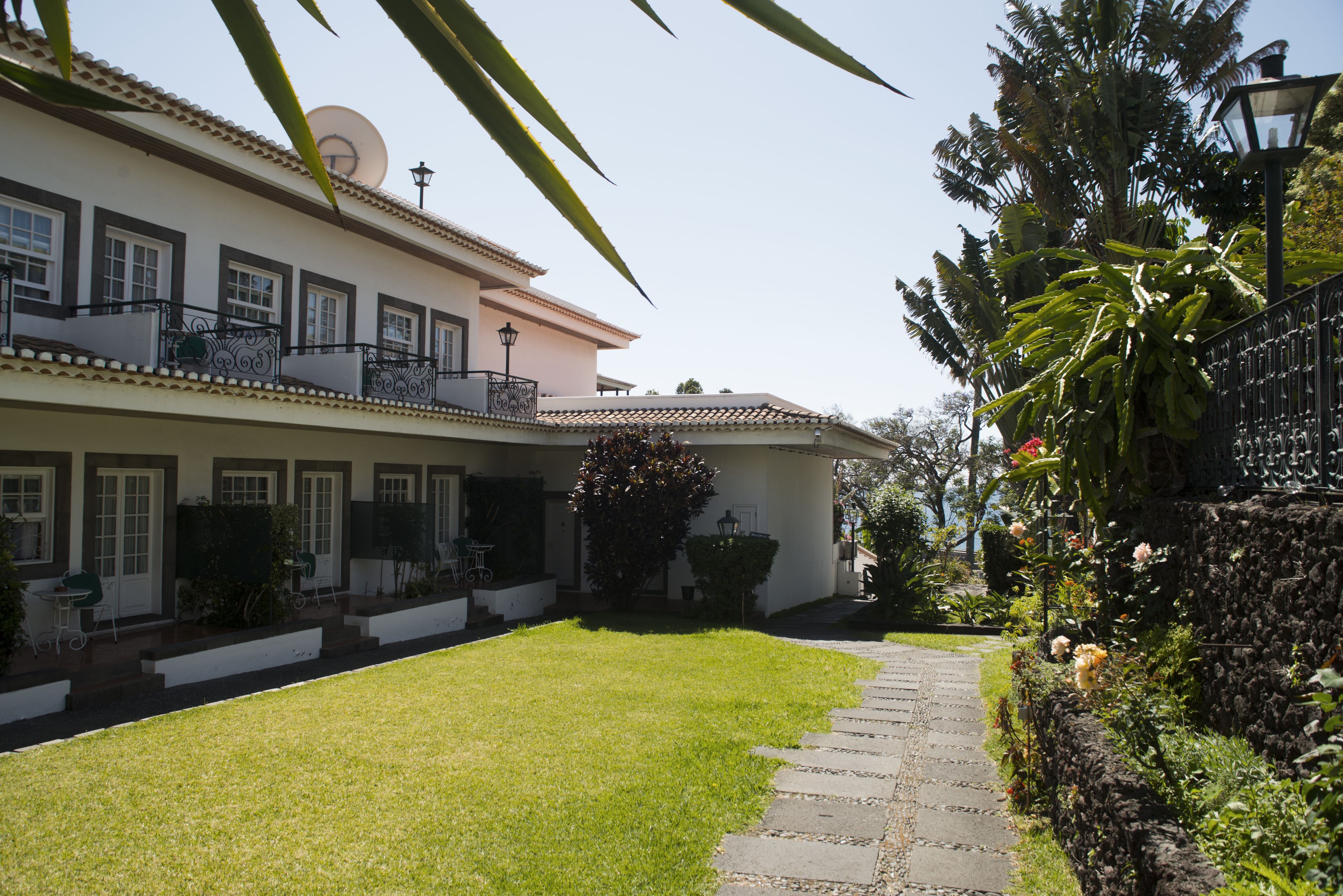 A two-story house with a well-maintained lawn, a stone pathway, and a balcony with a railing.