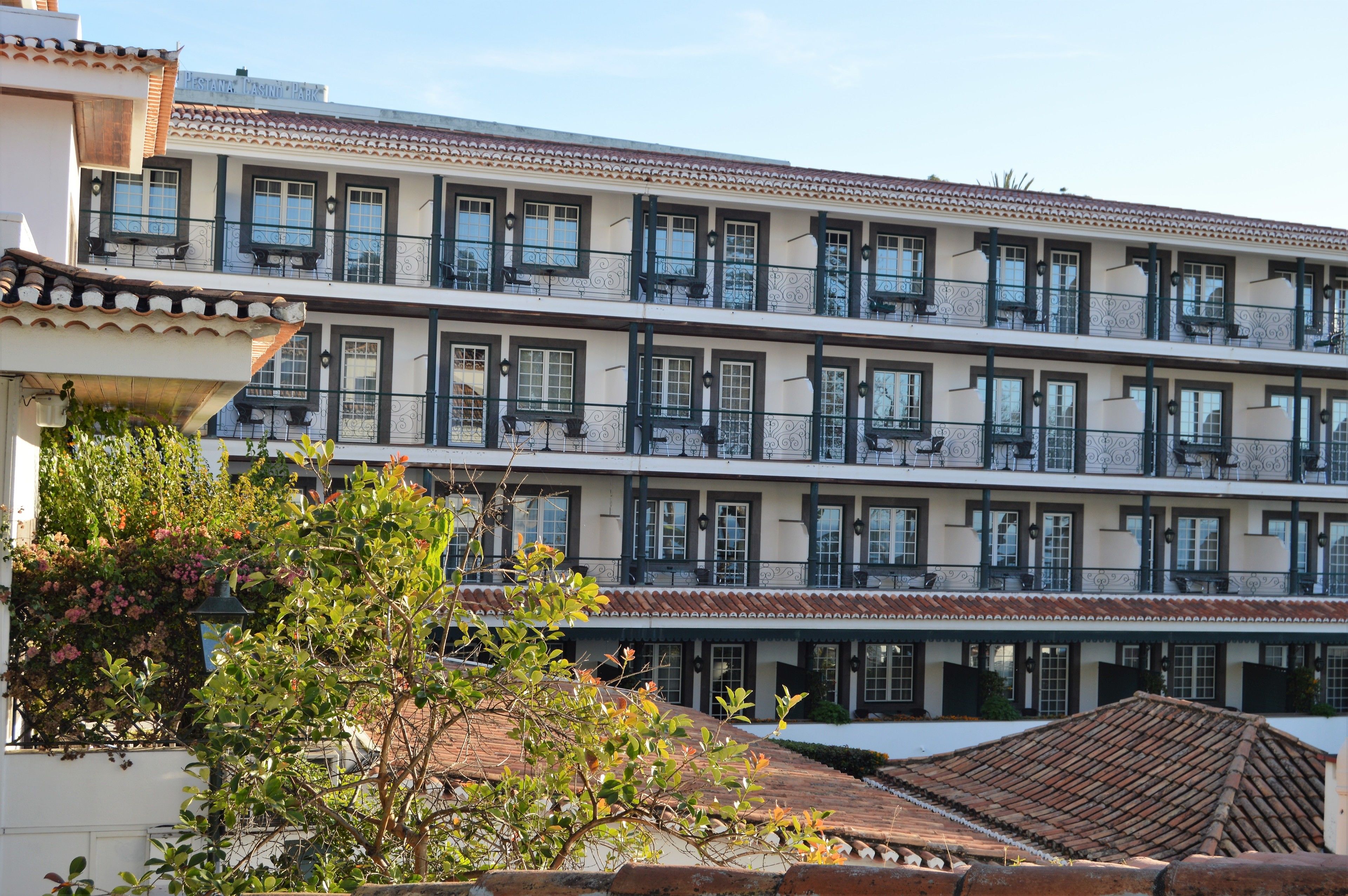 Un hotel de varios pisos con balcones, ventanas amplias y tejado de tejas.