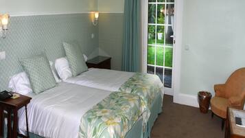 A neatly arranged bedroom with a bed, bedside tables, a chair, and a window with a view of greenery.