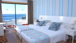 Ein Hotelzimmer mit Balkon, einem Bett mit gemustertem Überwurf, einem Nachttisch und einem Beistelltisch.