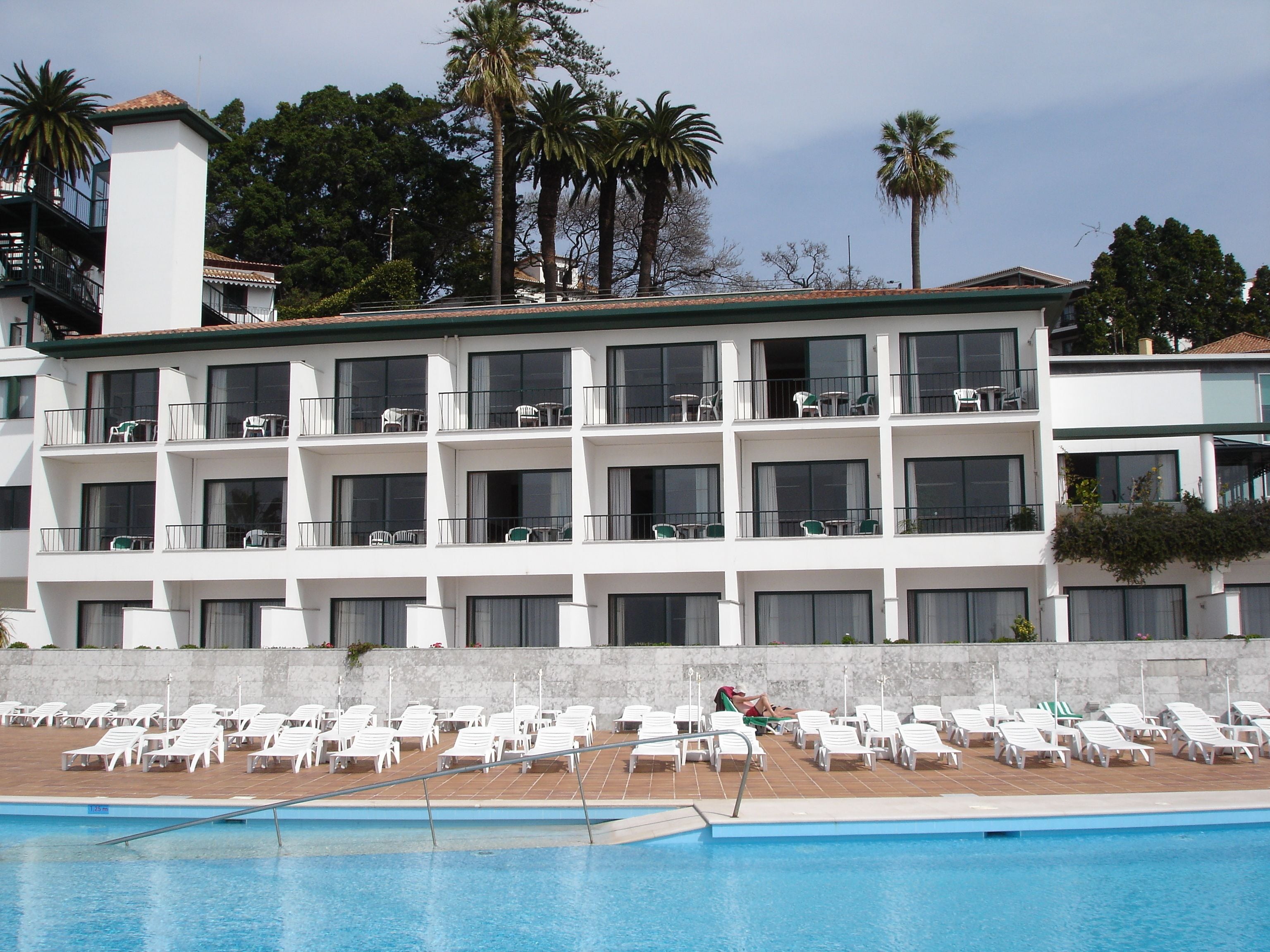 Un hôtel doté de nombreux balcons, d’une piscine et, en arrière-plan, de palmiers.