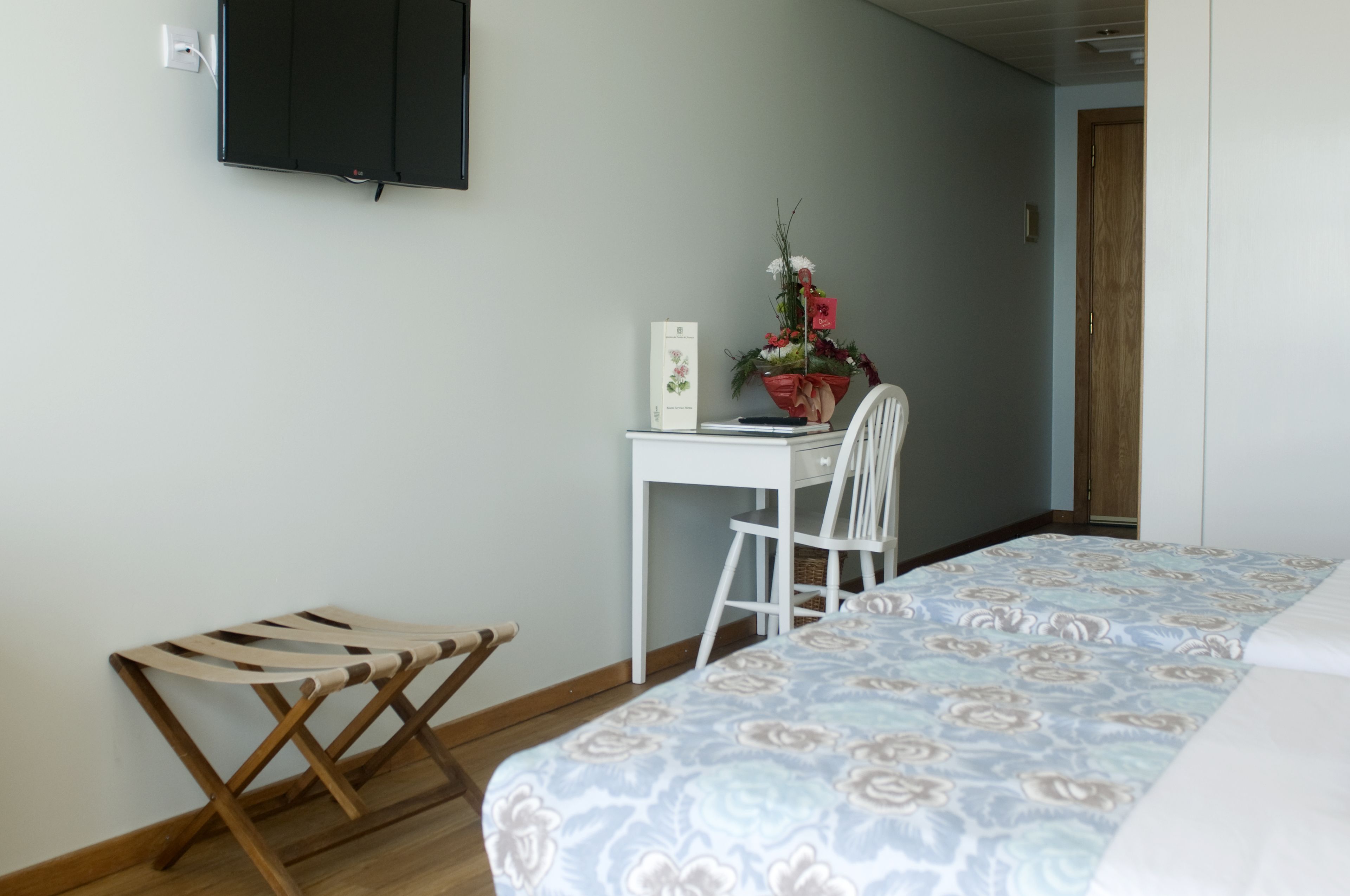 A bedroom with a bed, a desk, a chair, and a small wooden bench.