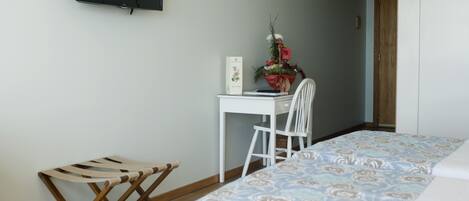 A bedroom with a bed, a desk, a chair, and a small wooden bench.