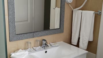 Un baño con un lavamanos blanco, un espejo con marco de granito, un secador de pelo y dos toallas colgadas en la pared.