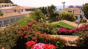 Ein Hotel mit Ziegeldach, umgeben von üppigem Grün und farbenprächtigen Blumen.