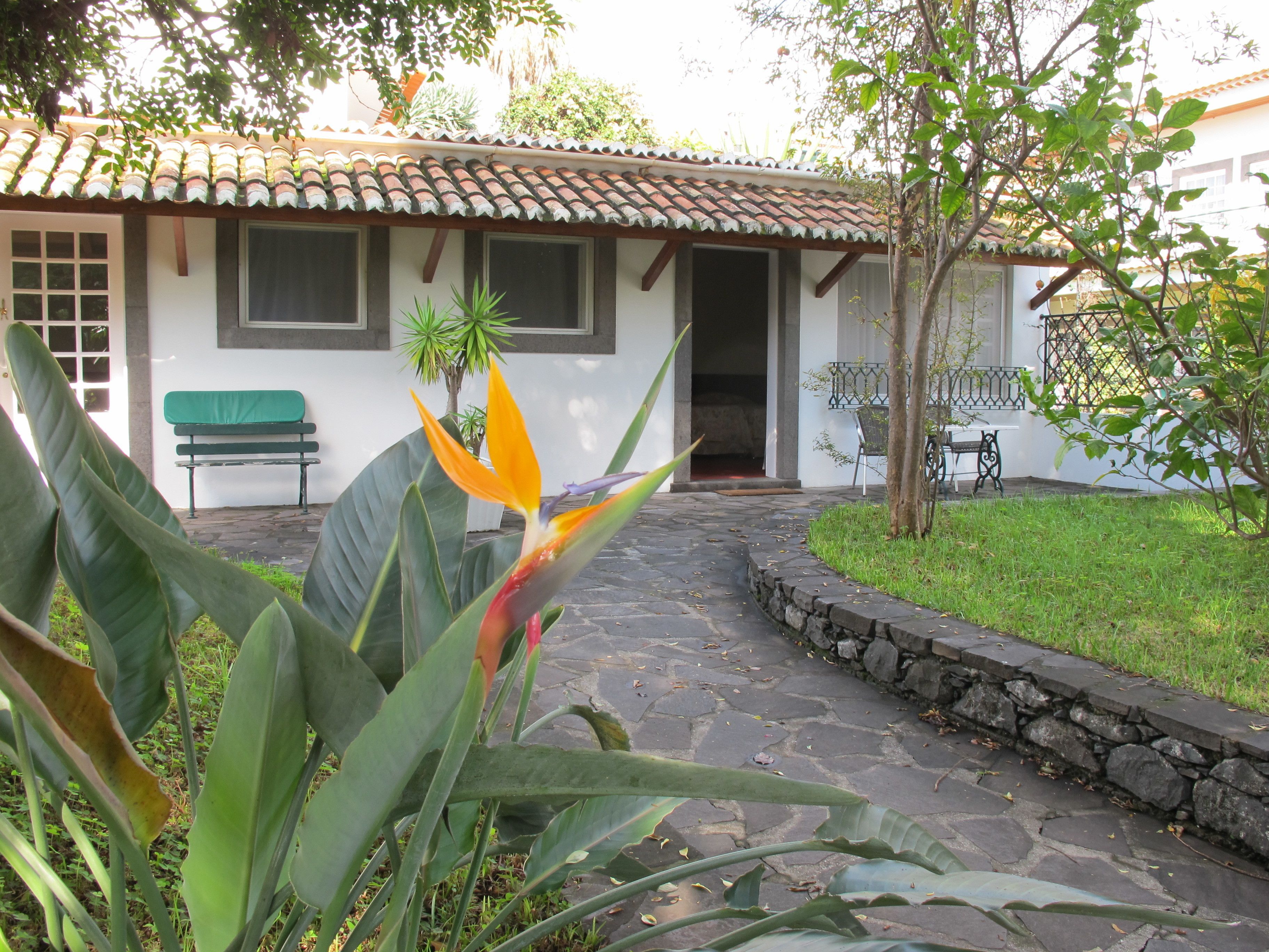 A building with a tiled roof, a stone pathway, and a bench.