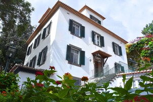 Ein weißes Gebäude mit grünen Fensterläden, einem Balkon und einer Treppe.