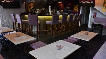 Un espace bar comprenant un comptoir, des tabourets de bar et des tables avec des chaises.
