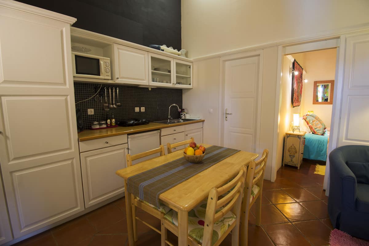 A compact kitchen with white cabinets, a microwave, and a dining table with chairs.