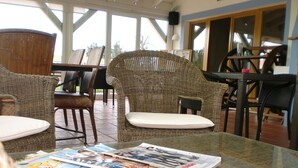 A glass-top table with magazines, wicker chairs, and a view of the outdoors. - Casa Vicentina (Aljezur)