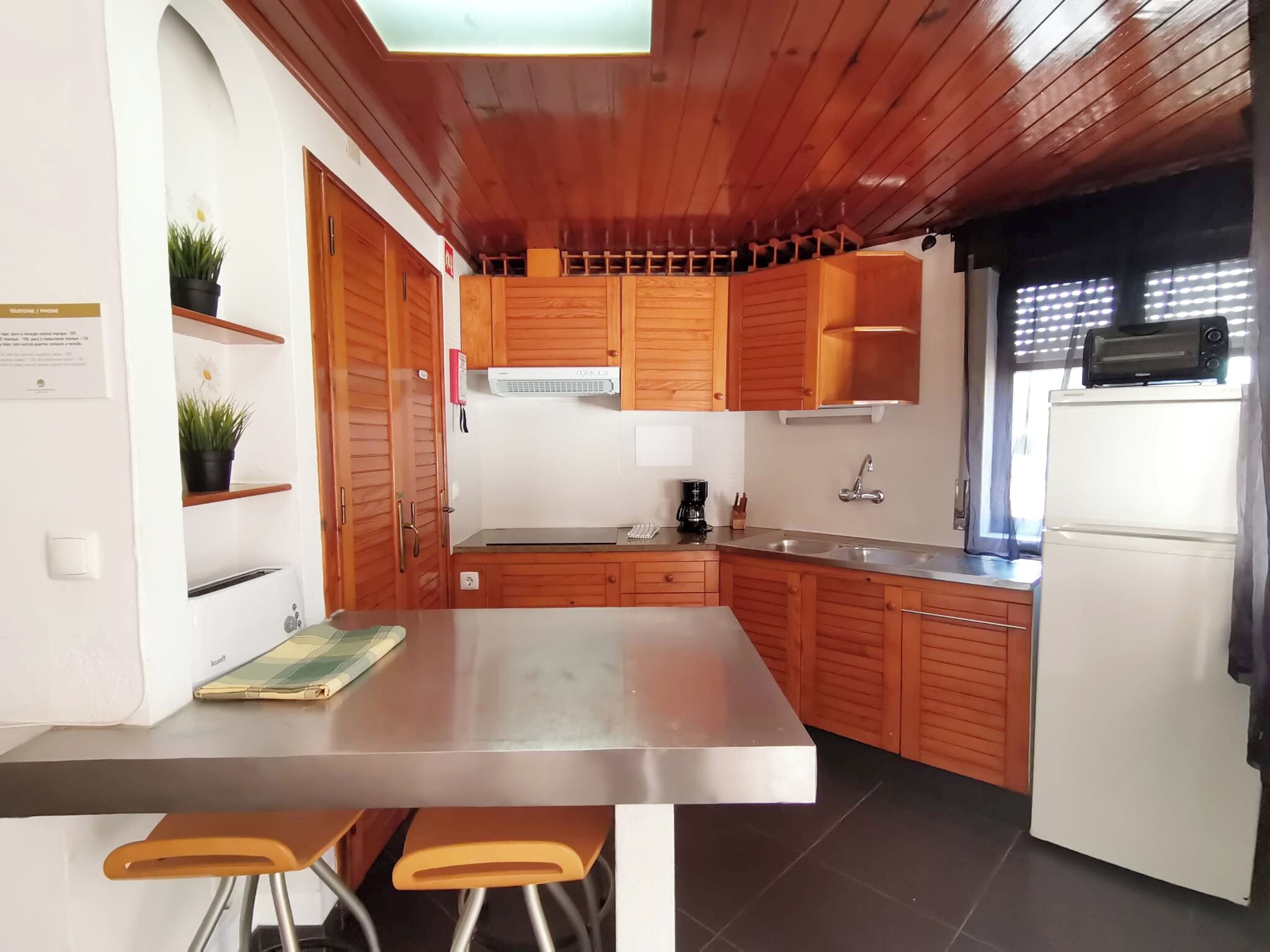 Une cuisine moderne avec des armoires en bois, un plan de travail en acier inoxydable, un four encastré et un réfrigérateur.