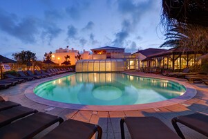 Una piscina techada, una piscina al aire libre, sombrillas