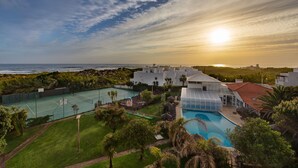 A resort with a tennis court, swimming pool, and a view of the ocean at sunset. - Duna Parque Beach Club - Duna Parque Resorts & Hotels (Odemira)