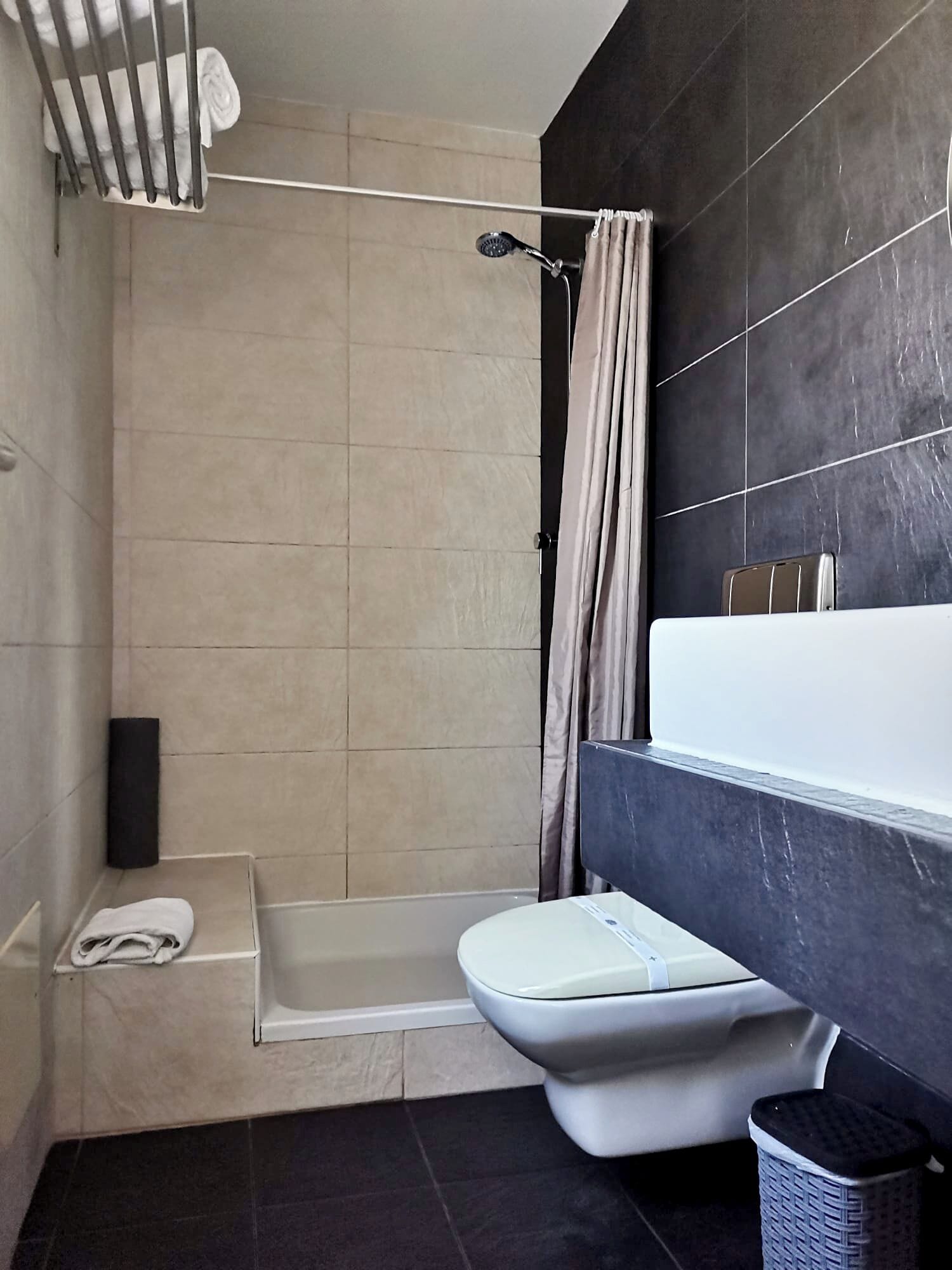 Une salle de bain moderne équipée d’une baignoire, de toilettes et d’un espace douche.