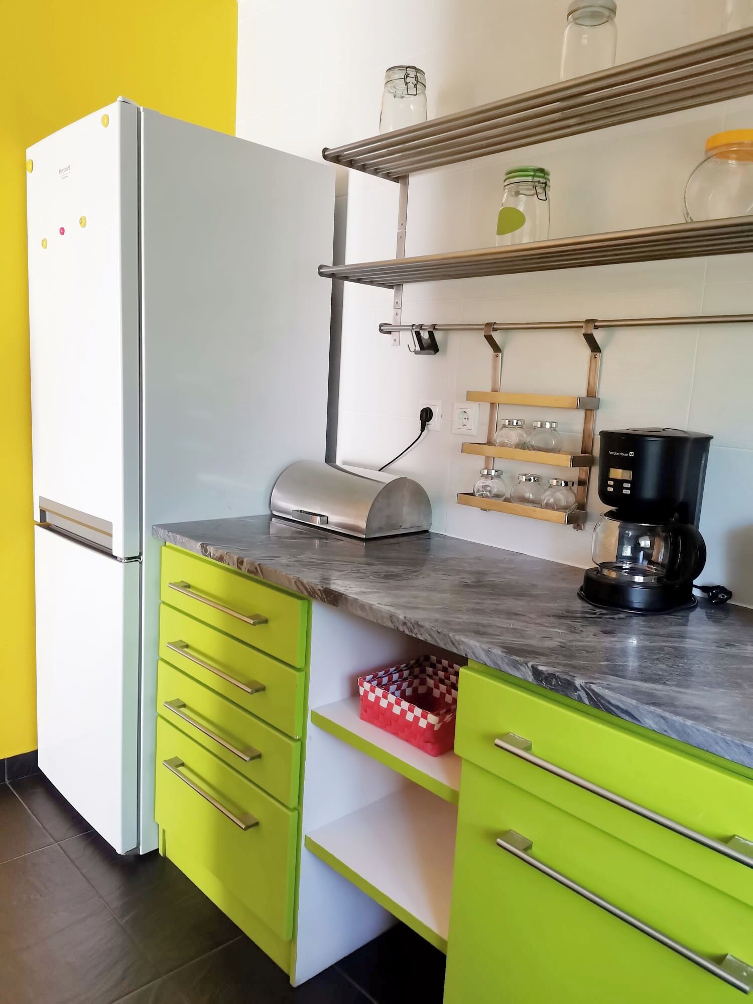 Eine Küche mit Kühlschrank, Kaffeemaschine und einer Regalanlage mit Gläsern.