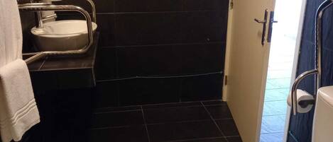 Et lille, moderne badeværelse med toilet, håndvask og håndtørrer.